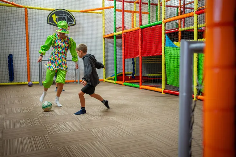 Animátor v kostýme hrá s chlapcom futbal