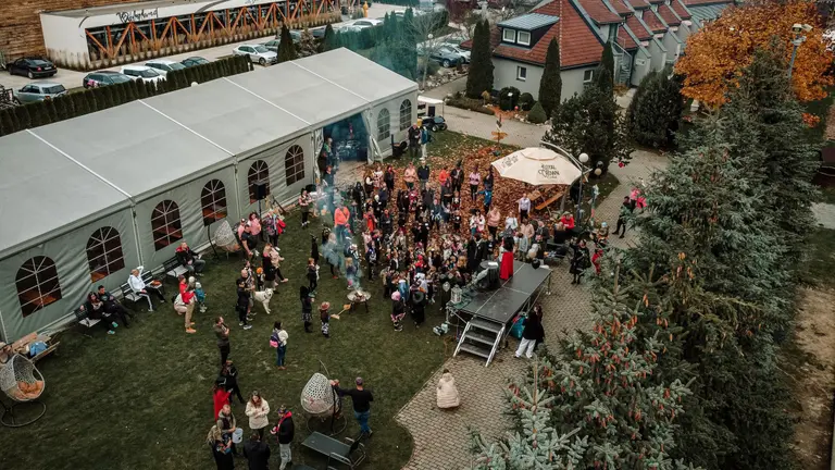 Dav ľudí v kostýmoch oslavuje pri pódiu a ohnisku vo Villa Betula Resort.