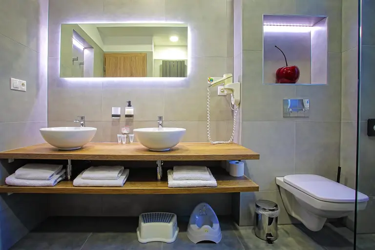 Moderná kúpeľňa vo Villa Betula Resort s dvoma umývadlami a detskými doplnkami.