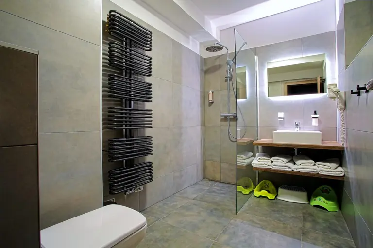 Moderná kúpeľňa so sprchou, umývadlom a detskými nočníkmi vo Villa Betula Resort.