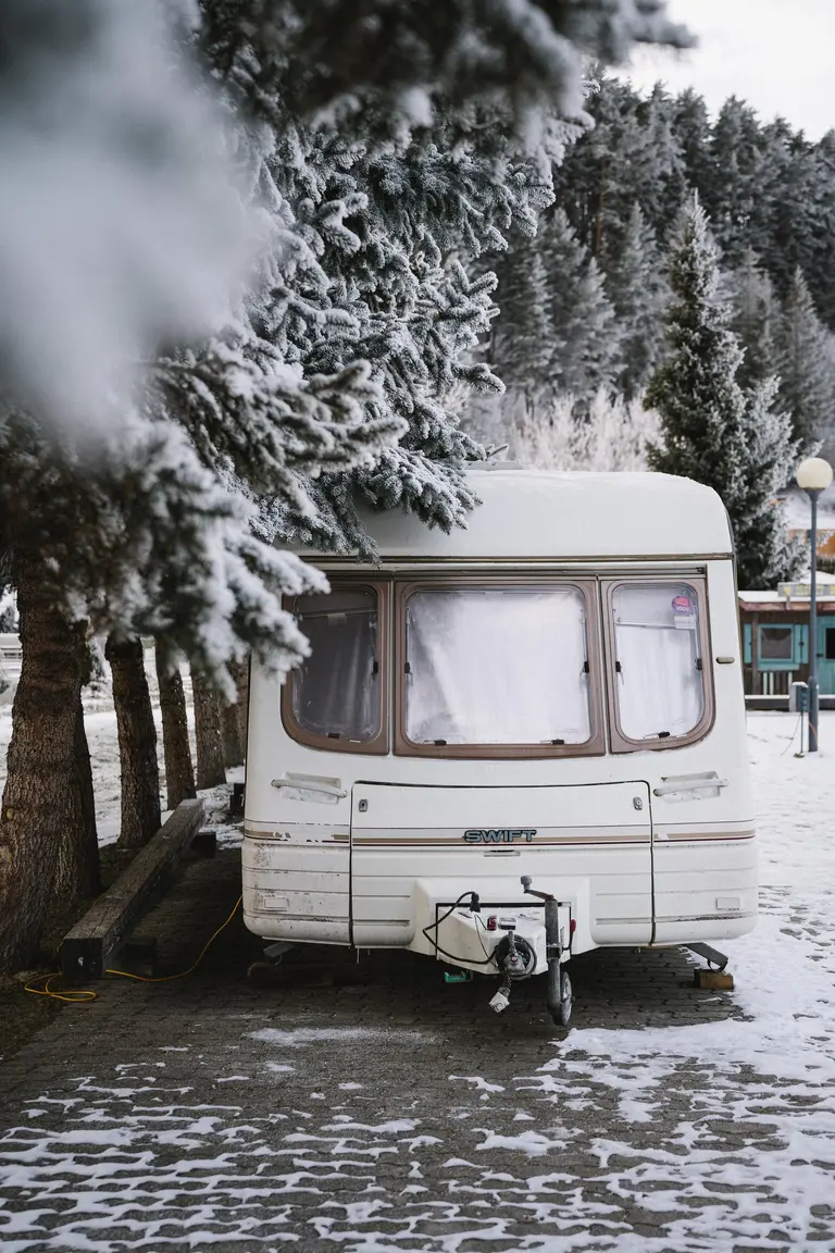 Biely karavan Swift stojí v zime pod zasneženými stromami vo Villa Betula Resort.