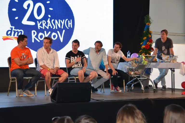 Päť mužov sedí na pódiu pred transparentom dm 20. krásnych rokov vo Villa Betula Resort.