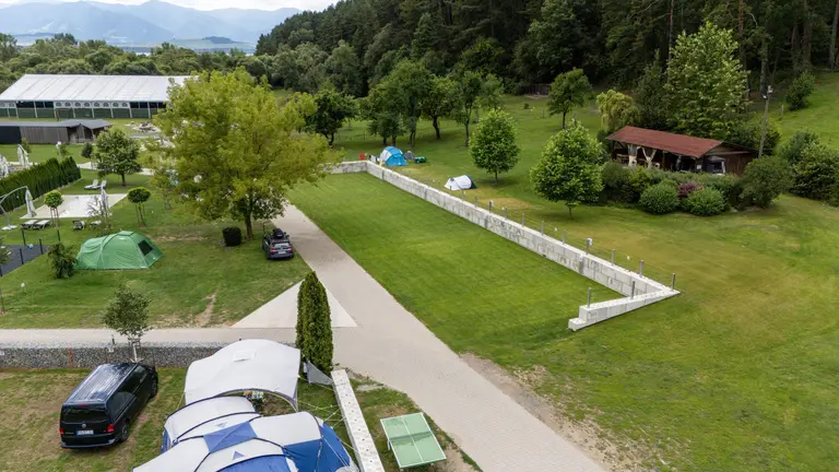 Kempingové stany, autá a zelená tráva s horami v pozadí vo Villa Betula Resort.