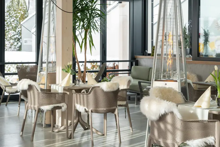 Reštaurácia vo Villa Betula Resort so stolmi, stoličkami s kožušinami a výhľadom na sneh.