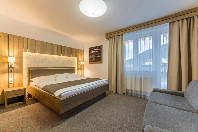 Príjemná manželská posteľ s dreveným čelom a lampami vo Villa Betula Resort.