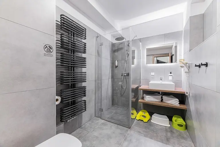 Moderná kúpeľňa s detskými pomôckami a sprchovacím kútom vo Villa Betula Resort.