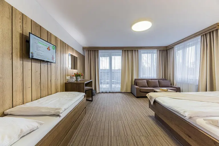 Pohodlná izba s dreveným obkladom, samostatnou posteľou a balkónom vo Villa Betula Resort.