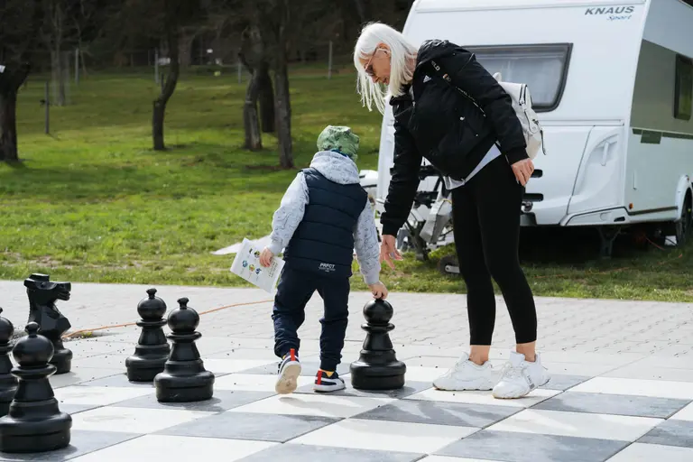Dieťa a dospelá osoba hrajú vonkajší šach vo Villa Betula Resort.
