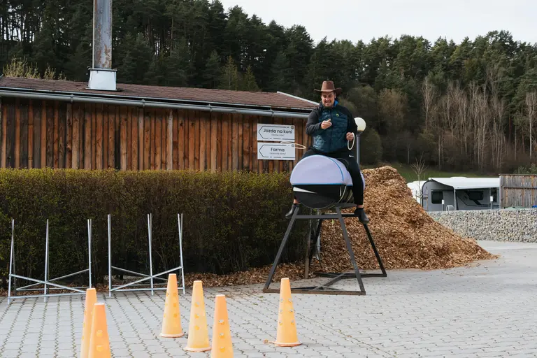 Muž na mechanickom býkovi pri drevenej stajni vo Villa Betula Resort.