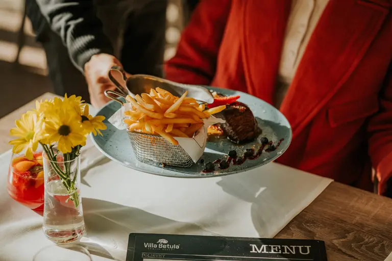 Čašníčka podáva steak s hranolčekmi