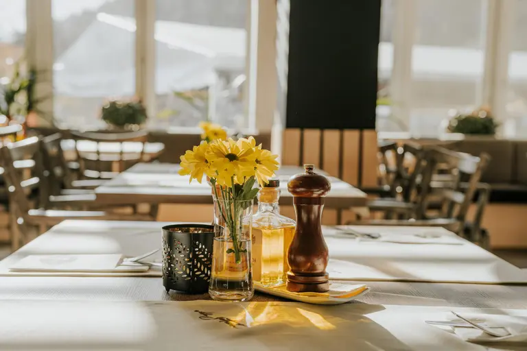 Stôl s kvetmi, koreničkou a olejom v reštaurácii Villa Betula Resort.