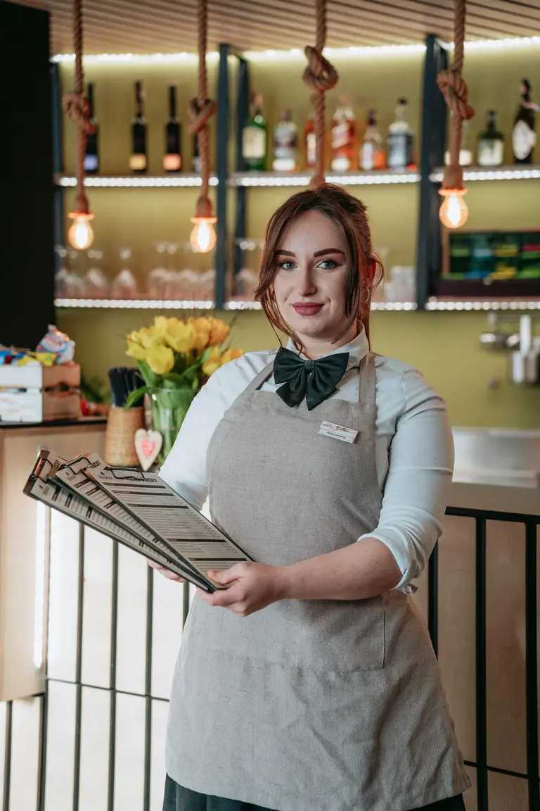 Pracovníčka rezortu s menu v rukách pri pulte vo Villa Betula Resort.